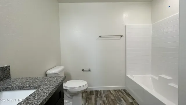 a bathroom with a granite countertop toilet and a bathtub