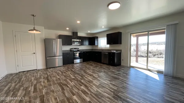 a kitchen with stainless steel appliances granite countertop a refrigerator a sink dishwasher a stove and a microwave oven on the wooden floor
