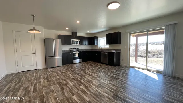 a kitchen with stainless steel appliances granite countertop a refrigerator a sink dishwasher a stove and a microwave oven on the wooden floor