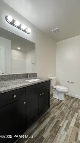 a spacious bathroom with a granite countertop sink a toilet and a mirror