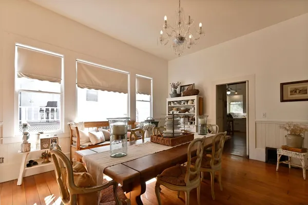 a kitchen with stainless steel appliances a stove top oven a refrigerator a dining table and chairs with wooden floor