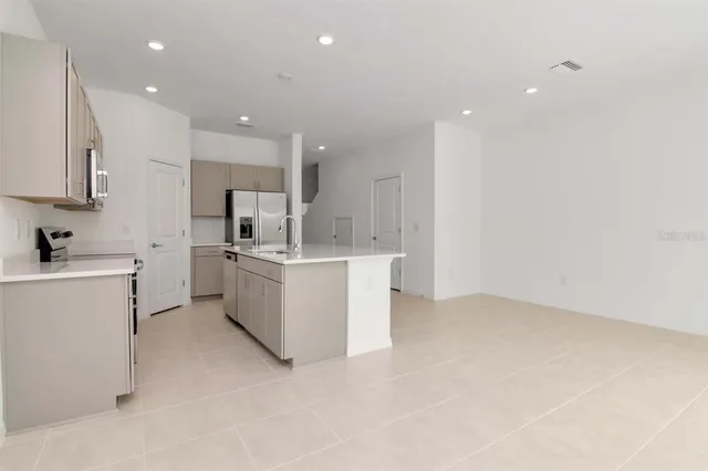 a view of a kitchen with kitchen island a sink stainless steel appliances and cabinets
