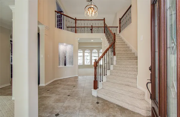 a view of staircase with railing and a chandelier