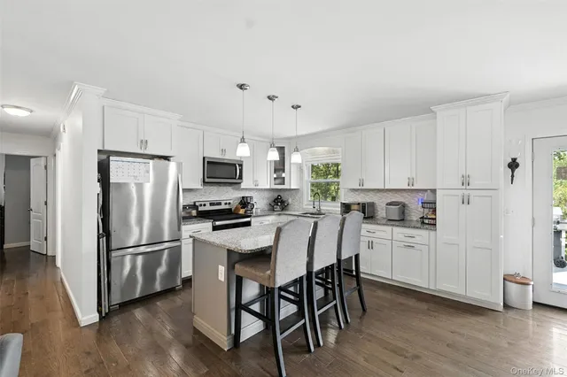 a kitchen with stainless steel appliances a stove a sink a microwave a dining table and chairs