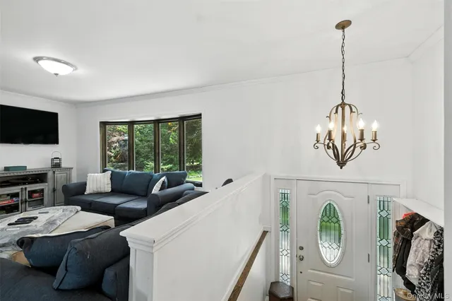 a living room with furniture a flat screen tv and a floor to ceiling window