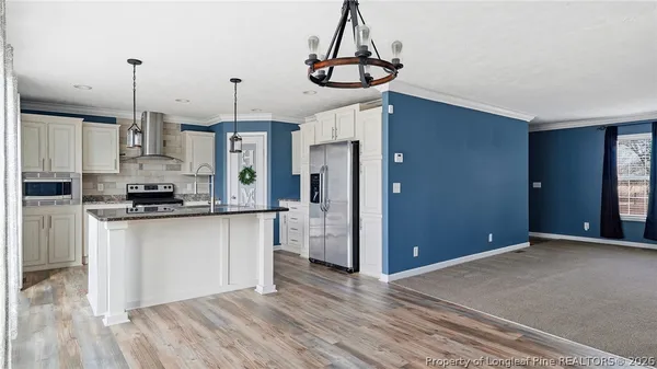 a kitchen with stainless steel appliances granite countertop a refrigerator a oven and white cabinets