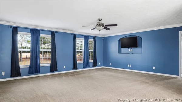 a view of an empty room with chandelier fan and window