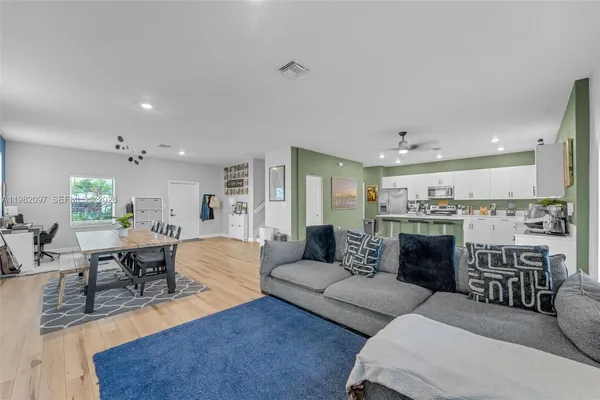 a living room with furniture wooden floor and kitchen view