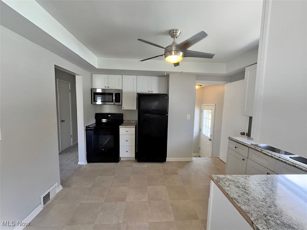 28642 Forest Road Willowick, OH 44095 - Photo 8 of 23 Kitchen featuring black appliances, white cabinets, ceiling fan, and a raised ceiling