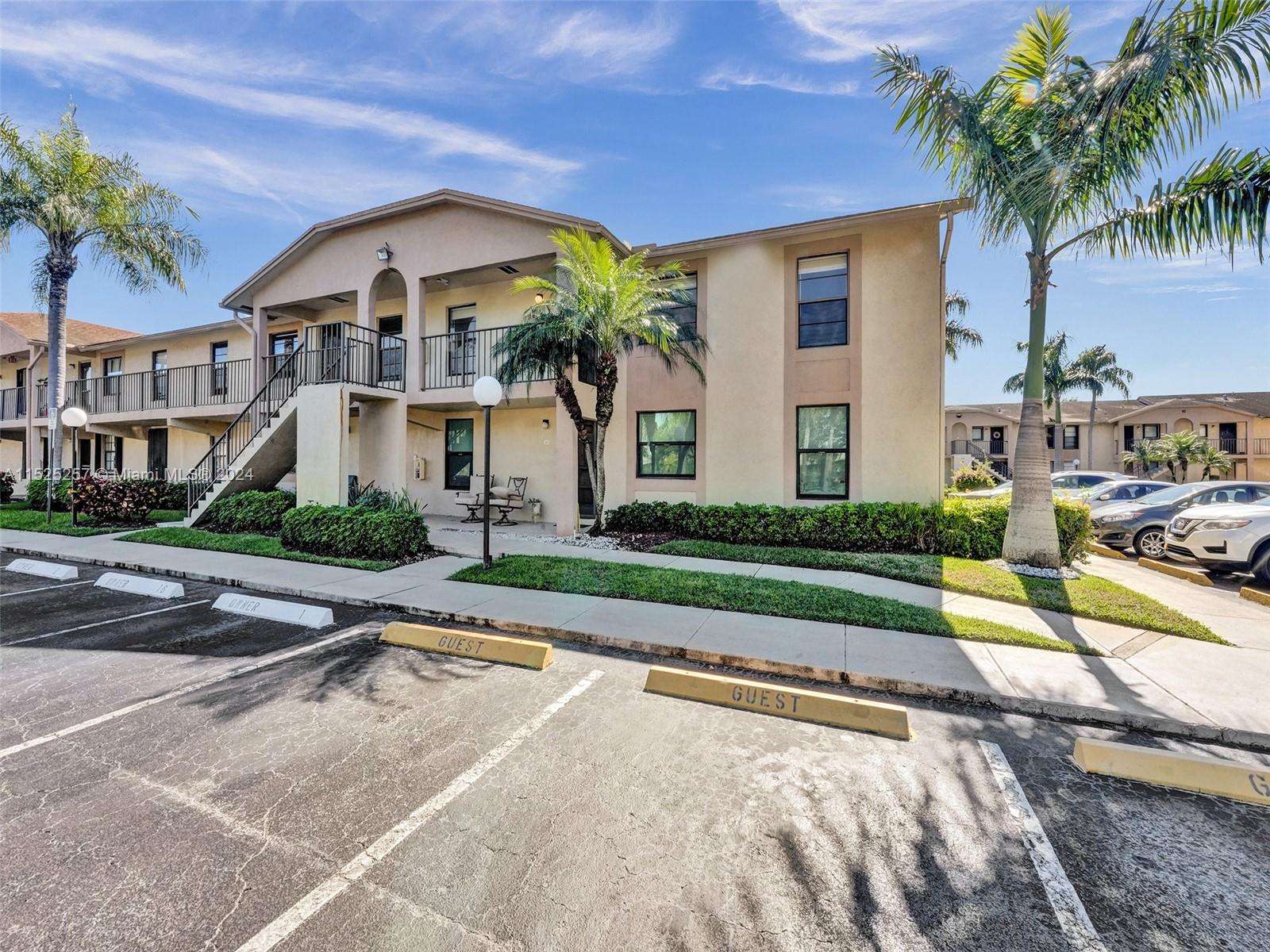 9480 Boca Cove Circle, Unit 416 Boca Raton, FL 33428 - Photo 18 of 25 a view of a white house with a small yard plants and palm trees