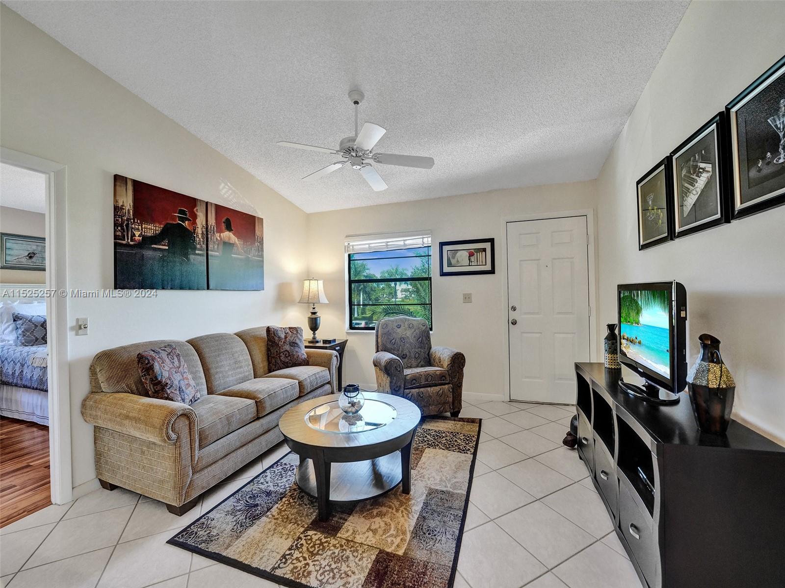 9480 Boca Cove Circle, Unit 416 Boca Raton, FL 33428 - Photo 4 of 25 a living room with furniture a flat screen tv and a window