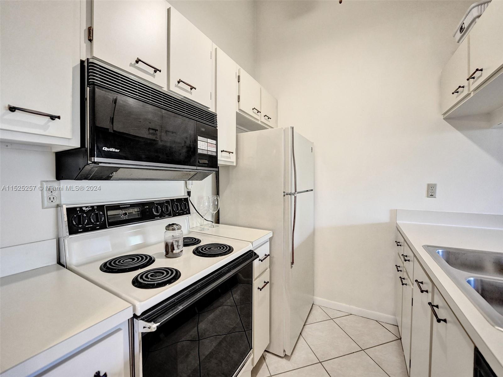 9480 Boca Cove Circle, Unit 416 Boca Raton, FL 33428 - Photo 5 of 25 a kitchen with a stove and a microwave