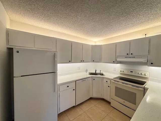 a kitchen with a sink a refrigerator and white cabinets