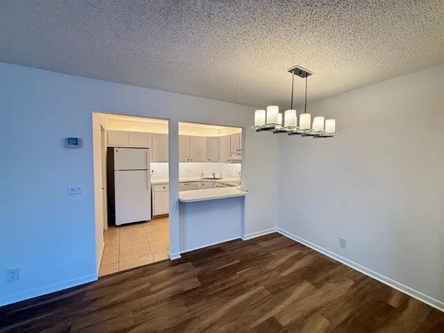 a view of a room with wooden floor and kitchen view