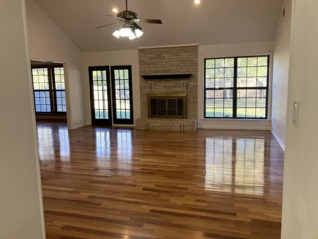 a view of an empty room with wooden floor and a window