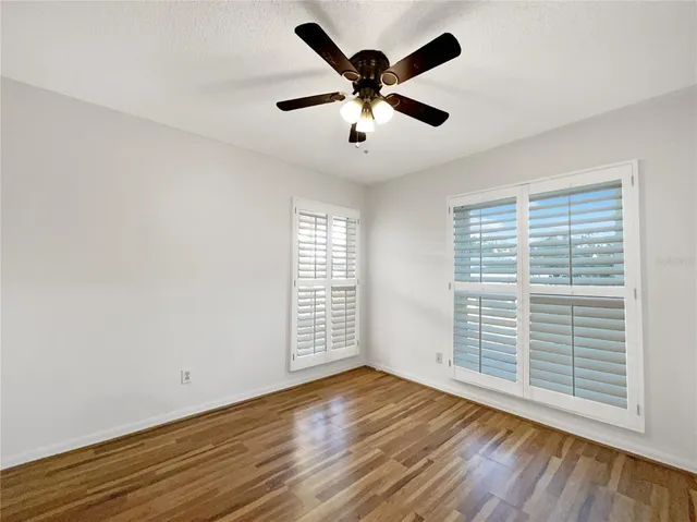 a view of empty room with wooden floor and fan