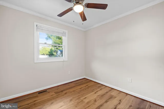 an empty room with wooden floor chandelier fan and windows