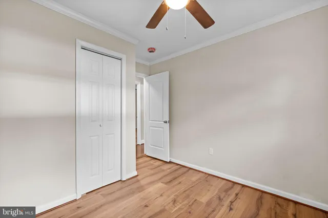 an empty room with wooden floor chandelier fan and windows