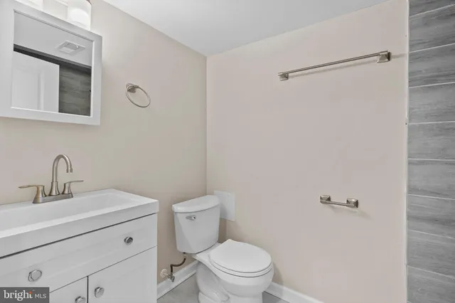 a bathroom with a toilet sink vanity and mirror