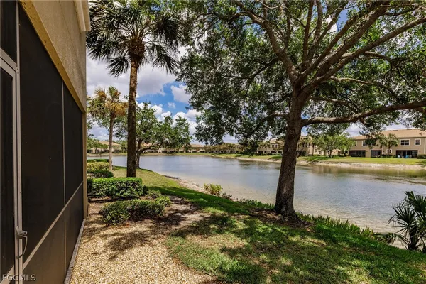 a view of a white house next to a yard with big trees