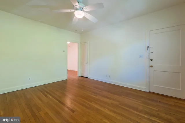 an empty room with wooden floor and fan