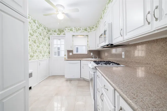 a kitchen with granite countertop white cabinets and white appliances