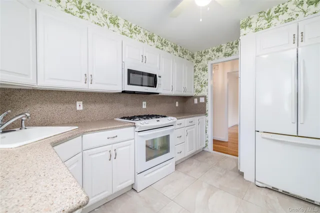 a kitchen with granite countertop white cabinets and white appliances