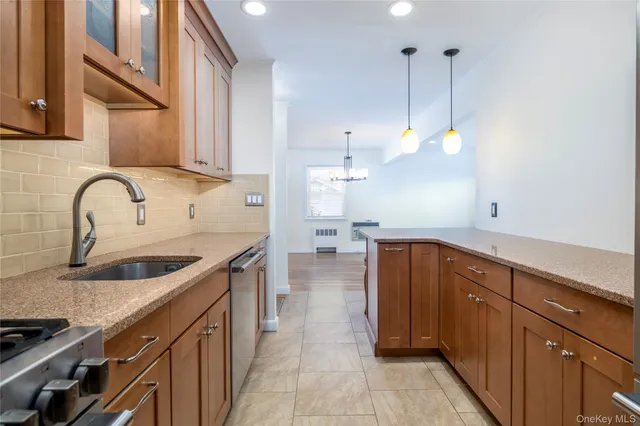 a kitchen with stainless steel appliances granite countertop a sink a stove and a wooden cabinets
