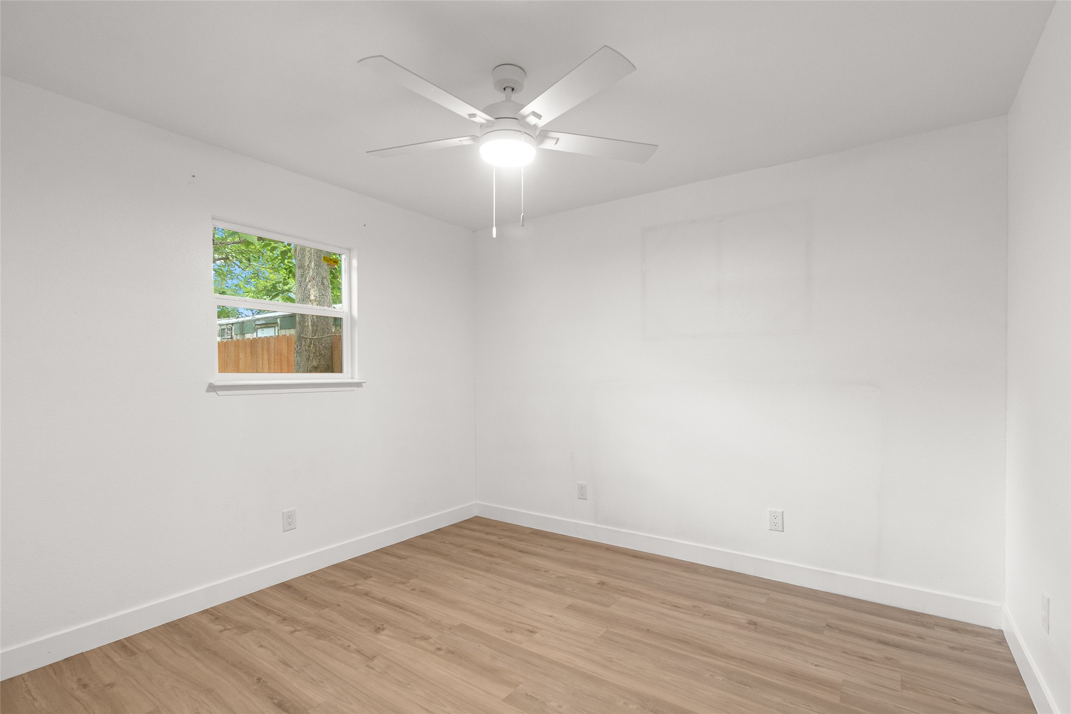 409 Ave R Marble Falls, TX 78654 - Photo 20 of 25 Bedroom featuring light wood-finish flooring, white painted walls, and a ceiling fan with integrated lighting
