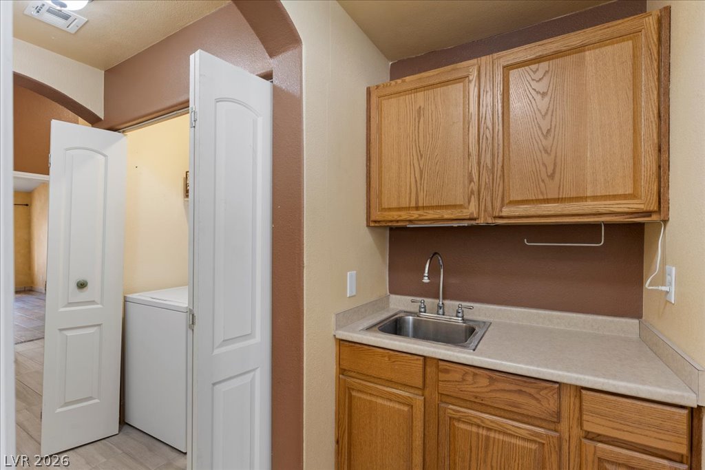 120 Ringlore Road Henderson, NV 89015 - Photo 43 of 58 Natural wood cabinetry and a functional utility sink bring convenience to this dedicated laundry space.