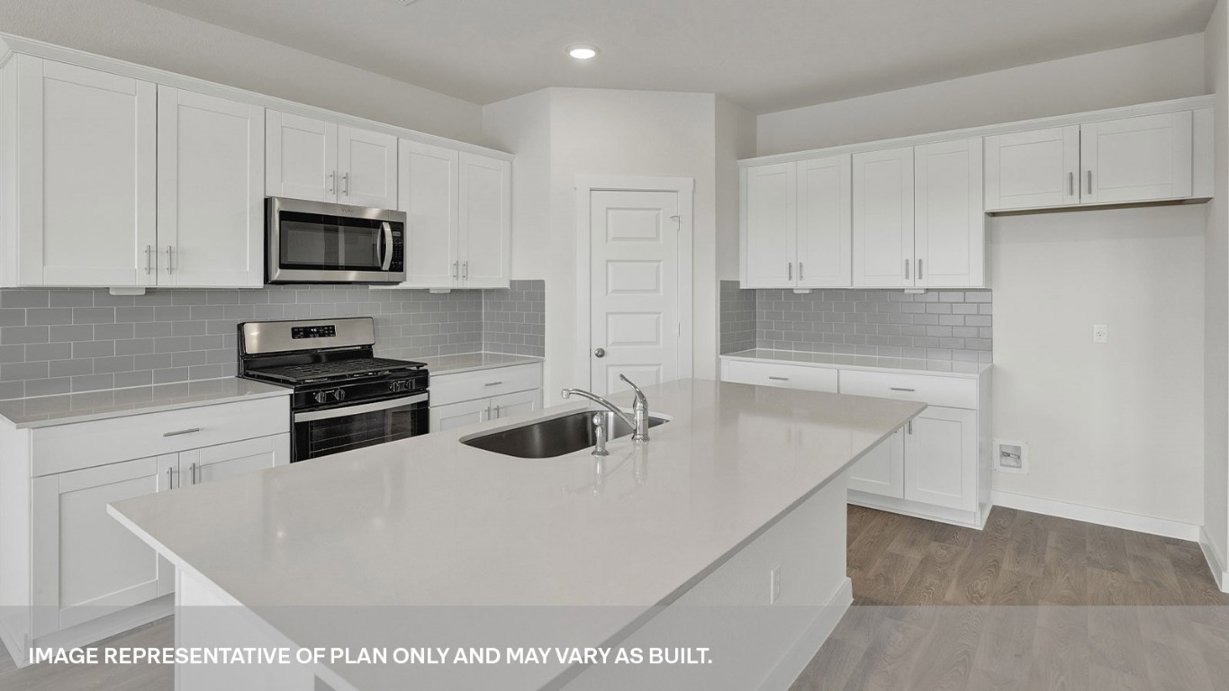 198 Kolbo Crossing Lockhart, TX 78644 - Photo 19 of 23 a kitchen with stainless steel appliances a stove a sink a microwave and cabinets