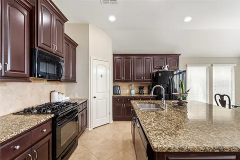 a kitchen with granite countertop stainless steel appliances a sink a stove cabinets and a counter top space