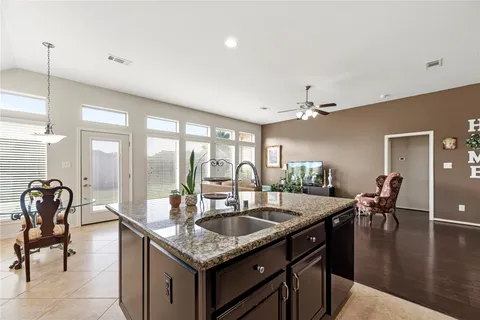 a kitchen with granite countertop a sink a counter top space and living room view
