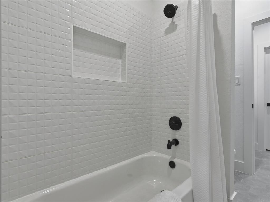 4211 Azalea Way Midlothian, TX 76065 - Photo 34 of 39 Contemporary tub and shower combination featuring black fixtures, white textured tile surround, and a recessed shower niche