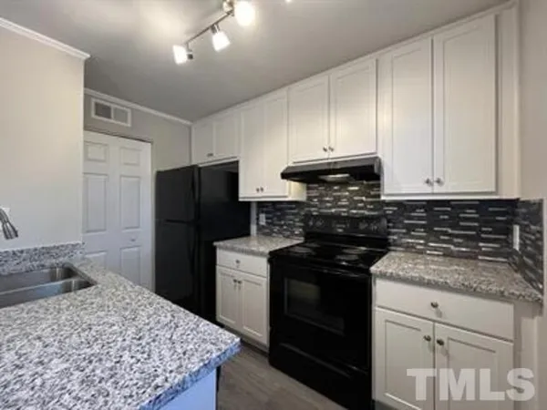 a kitchen with granite countertop a sink a stove and cabinets