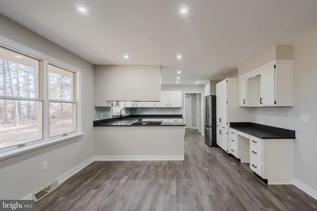 a large kitchen with stainless steel appliances granite countertop a stove a sink and a refrigerator