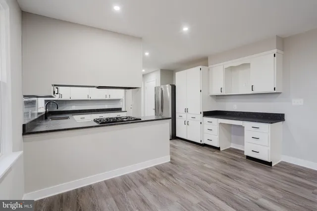 a kitchen with granite countertop a refrigerator and a stove top oven