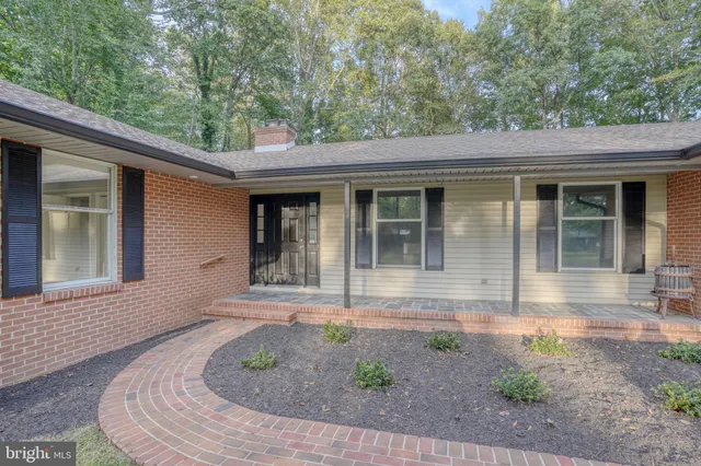 a aerial view of a house next to a yard with plants and large trees