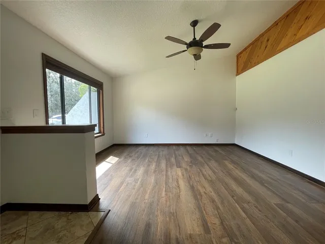 an empty room with wooden floor fan and windows