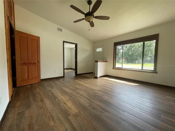 a view of an empty room with a window and wooden floor