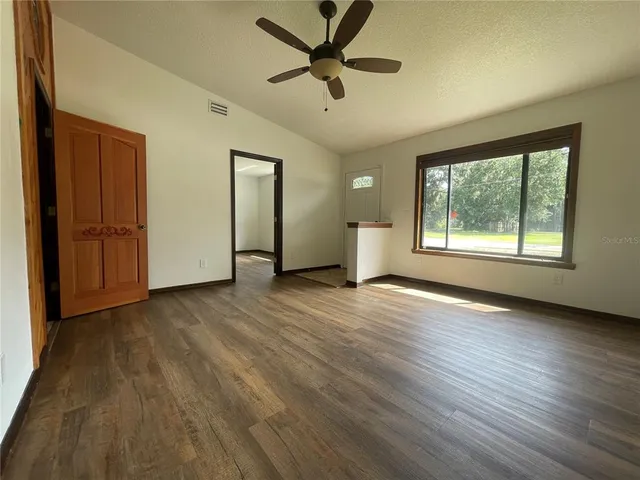 a view of an empty room with a window and wooden floor