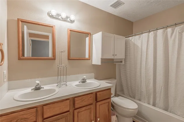 a bathroom with a double vanity sink toilet and a mirror