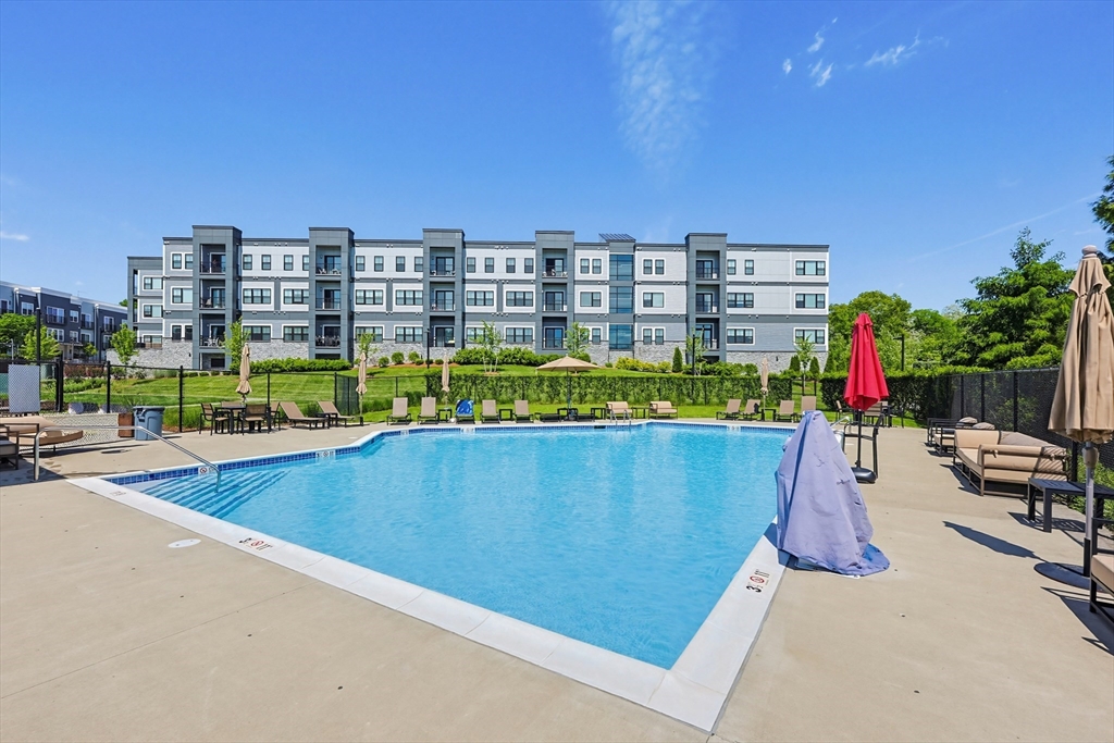 200 Revere Street, Unit 4209 Canton, MA 02021 - Photo 29 of 35 a view of swimming pool with outdoor seating and a buildings in the background