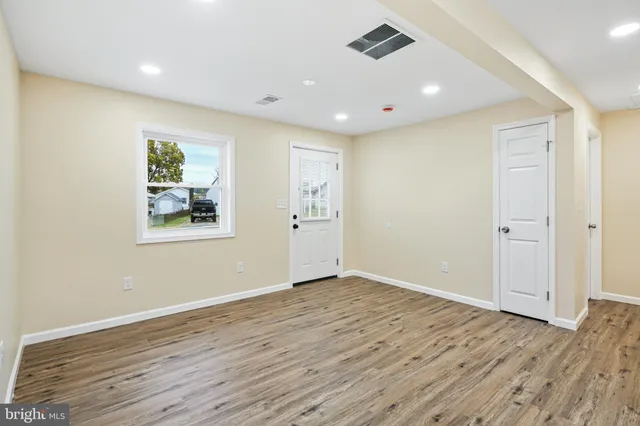 an empty room with wooden floor and windows