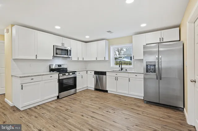 a kitchen with white cabinets stainless steel appliances and a window
