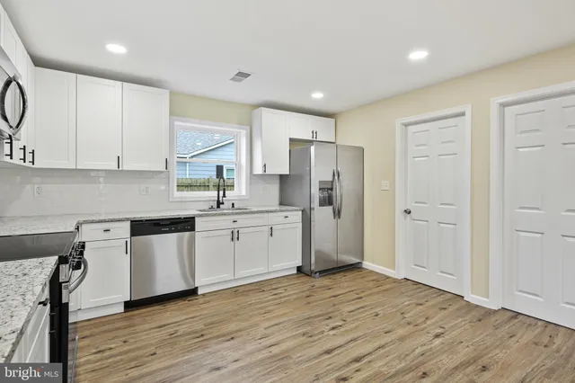 a kitchen with stainless steel appliances granite countertop a refrigerator sink and white cabinets