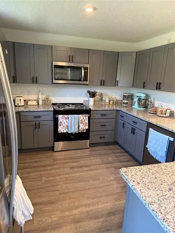 a kitchen with stainless steel appliances granite countertop a stove top oven a sink dishwasher and a refrigerator