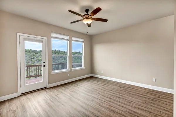 a view of an empty room with wooden floor and a ceiling fan