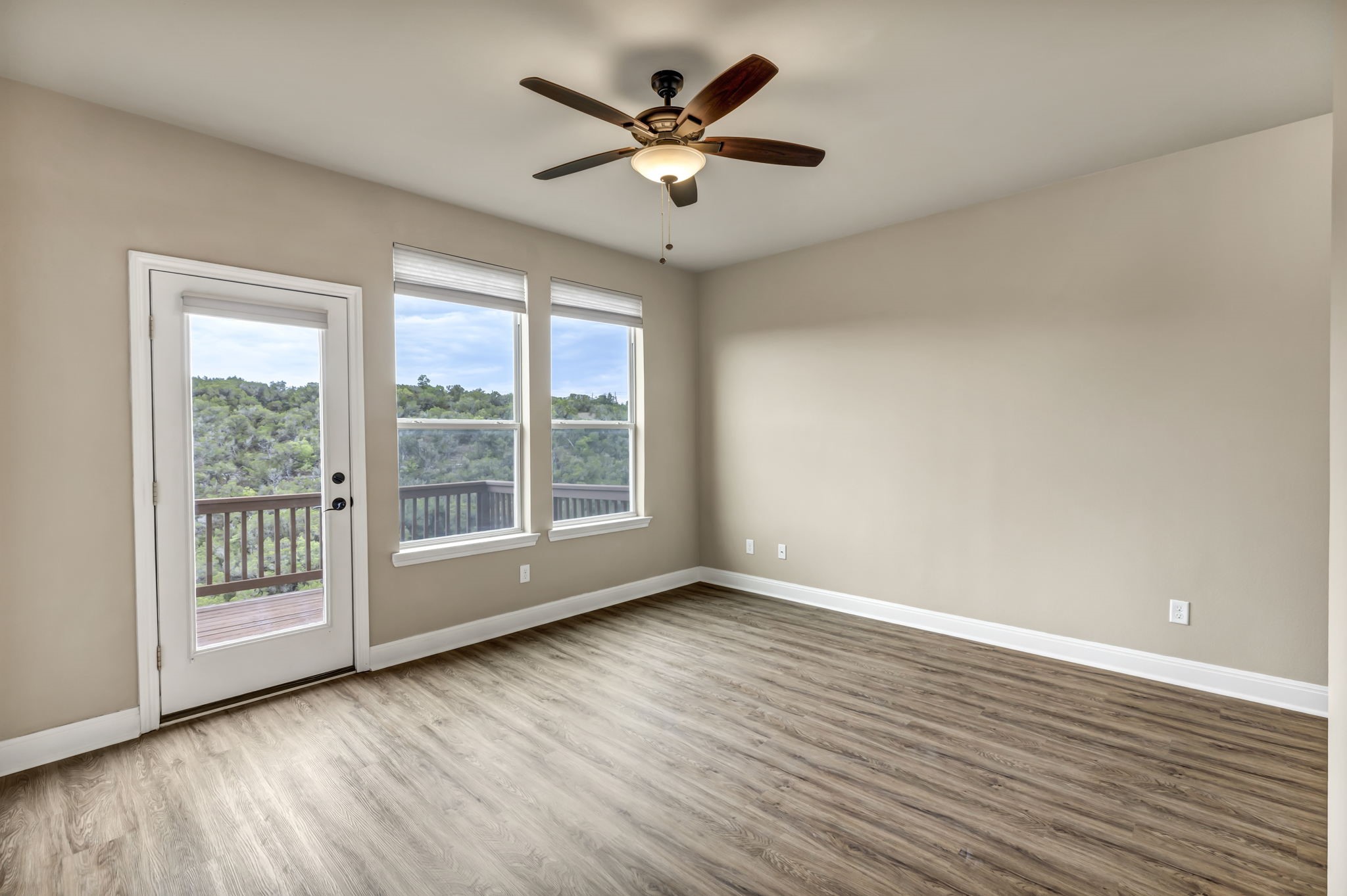 206 Sunrise Ridge Cove Austin, TX 78738 - Photo 11 of 38 a view of an empty room with wooden floor and a ceiling fan