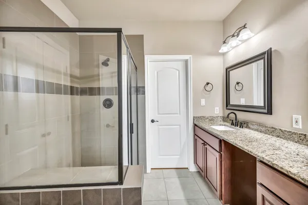 a bathroom with a granite countertop shower sink and mirror